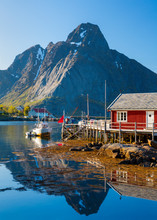 Reine Village On The Lofoten Islands,  Norway. The Typical Norwegian Fishing Village Of Reine Under Midnight Sun,  With The Typical Rorbu Houses.  Mountain In Background