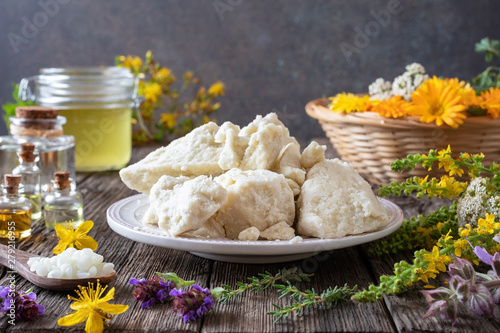 Shea butter on a plate, essential oils and herbs