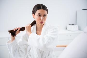 Wall Mural - Young brunette lady holding thick hair ponytail