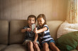 © Cavan for Adobe - Siblings taking selfie with smartphone on sofa