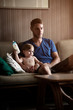 © Cavan for Adobe - Father sitting with baby son (12-17 months) on sofa
