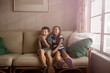 © Cavan for Adobe - Friends (8-9) with smart phone sitting on sofa