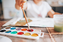 Beautiful Blonde Girl Painting With Paintbrush And Water Colors In The Kitchen. Kid Activities Concept. Close Up. Toned.