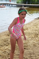 little girl in swimwear on the shore of the lake