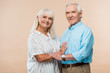 © LIGHTFIELD STUDIOS - cheerful senior couple smiling while standing on beige