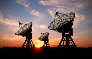 three sattelite dishes at sunset