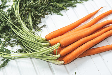 Gorgeous bunch of picked carrots with the leaves still on the stalks laying on an antique box.