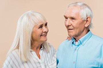 Wall Mural - happy retired woman looking at man with grey hair isolated on beige