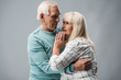 © LIGHTFIELD STUDIOS - senior man with grey hair hugging upset wife on grey