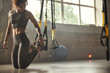 © Friends Stock - Young athletic woman in sports clothing adjusting trx fitness straps while training in the gym.