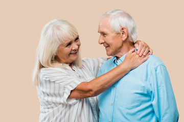 Wall Mural - happy retired woman hugging senior husband isolated on beige