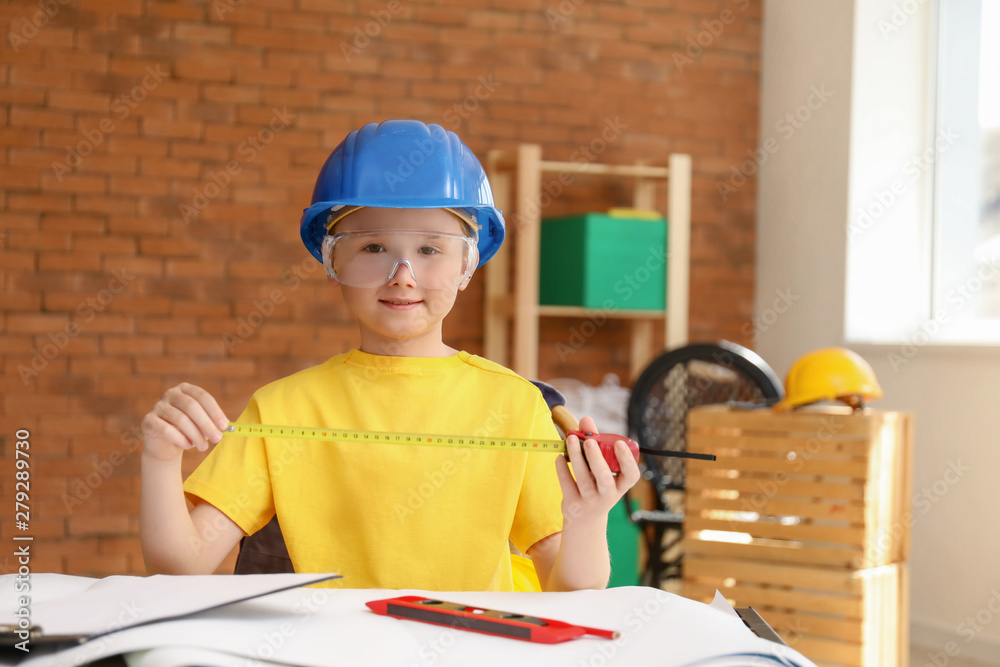 Cute little architect at table indoors