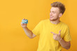 © Pixel-Shot - Happy young man with credit card on color background