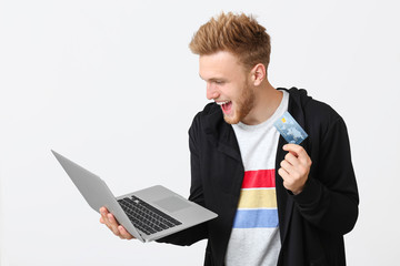 Sticker - Happy young man with credit card and laptop on white background