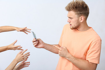 Wall Mural - Hands stretching to stressed young man with credit cards on white background