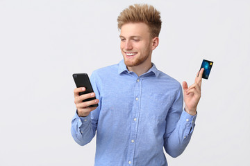 Canvas Print - Happy businessman with credit card and mobile phone on white background