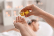 © Pixel-Shot - Massage therapist pouring essential oil onto hand in spa salon