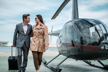 Young business couple near private helicopter