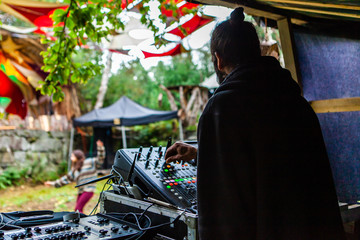 Wall Mural - Fusion of cultural & modern music event. An over the shoulder view of bohemian DJ using electronic music equipment to entertain people during a music festival celebrating a mix of modern & old sounds