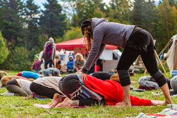 Wall Mural - Fusion of cultural & modern music event. People are seen relaxing and stretching in a festival campsite, as a bohemian styled person performs lumbar back massage on one person.