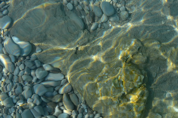 Wall Mural - Sea stones in the sea water. Pebbles under water. The view from the top. Nautical background. Clean sea water. Transparent sea.