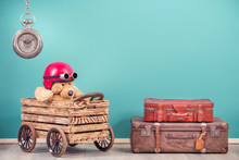 Teddy Bear Toy In Red Helmet With  Goggles In Hand Made Wooden Box With Retro Car Wheels Concept, Antique Leather Travel Luggage, Old Clock Front Mint Blue Background. Vintage Style Filtered Photo