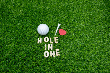 Wall Mural - Golf hole in one with golf ball and tee on green grass.