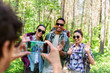 © Syda Productions - travel, tourism and hike concept - group of friends with backpacks being photographed by smartphone in forest