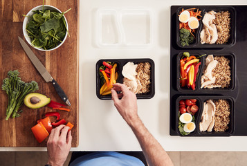 Overhead Shot Of Man Preparing Batch Of Healthy Meals At Home In Kitchen