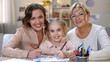 © motortion - Happy child with mother and granny drawing pencils smiling on camera, family