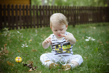 little boy sitting on green grass in the park