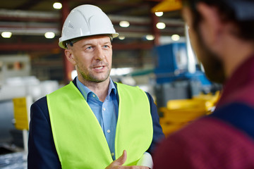 Engineers in hard hats talking to each other at the industrial plant.