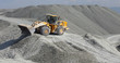 Wheel loader excavator against the background of gravel storage, panorama. Mining industry. Quarry and mining equipment.