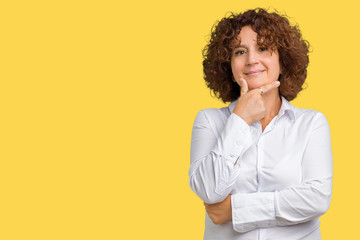 Beautiful middle ager senior businees woman over isolated background looking confident at the camera with smile with crossed arms and hand raised on chin. Thinking positive.