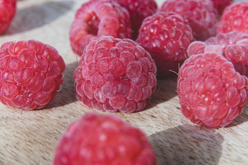 Wall Mural - Fresh organic raspberries background closeup. Fresh raspberries on wooden background; berries are lit with the daylight