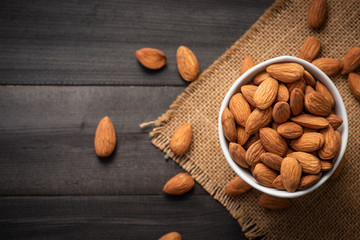 Wall Mural - Almonds in ceramic bowl on dark wood table. Almond concept with copyspace.