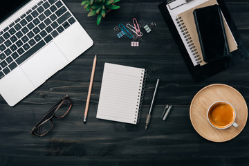 Aufkleber - Modern dark wood office desk table with laptop, smartphone and other supplies with cup of coffee. Blank notebook page for input the text in the middle. Top view, flat lay.