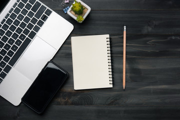 Aufkleber - Modern dark wood office desk table with laptop, smartphone and other supplies. Blank notebook page for input the text in the middle. Top view, flat lay.