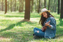 A Beautiful Asian Woman Sitting And Playing Ukulele In The Park