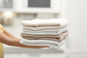 Sticker - Woman holding folded clean towels in kitchen, closeup. Laundry day