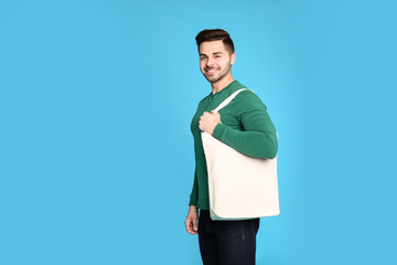 Wall Mural - Portrait of young man with eco bag on blue background. Space for text