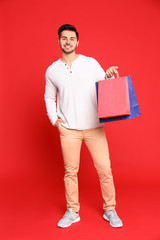 Canvas Print - Full length portrait of young man with paper bags on red background