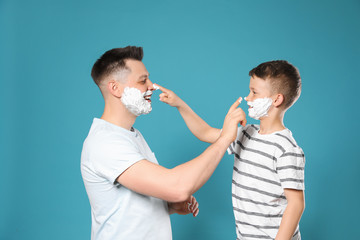 Sticker - Happy dad and son with shaving foam on faces against blue background