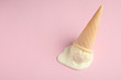 Melted vanilla ice cream in wafer cone on pink background, above view. Space for text
