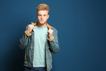 Wall Mural - Young man wearing blank t-shirt on blue background. Mockup for design