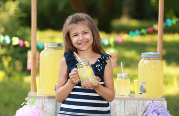 Cute little girl with natural lemonade in park. Summer refreshing drink