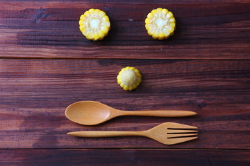 pieces of corn instant cooking with wooden spoon and fork on brown wood table