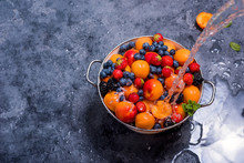 Water Splashing On Fresh Summer Fruits And Berries, Apricots, Blueberries, Strawberries In Colander, Washing Fruits And Berries, Vegan Healthy Food