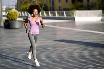 Wall Mural - Black woman, afro hairstyle, running outdoors in urban road.