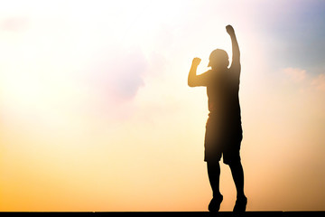 The boy jumped, raised his hand, happy to reach the goal. silhouette